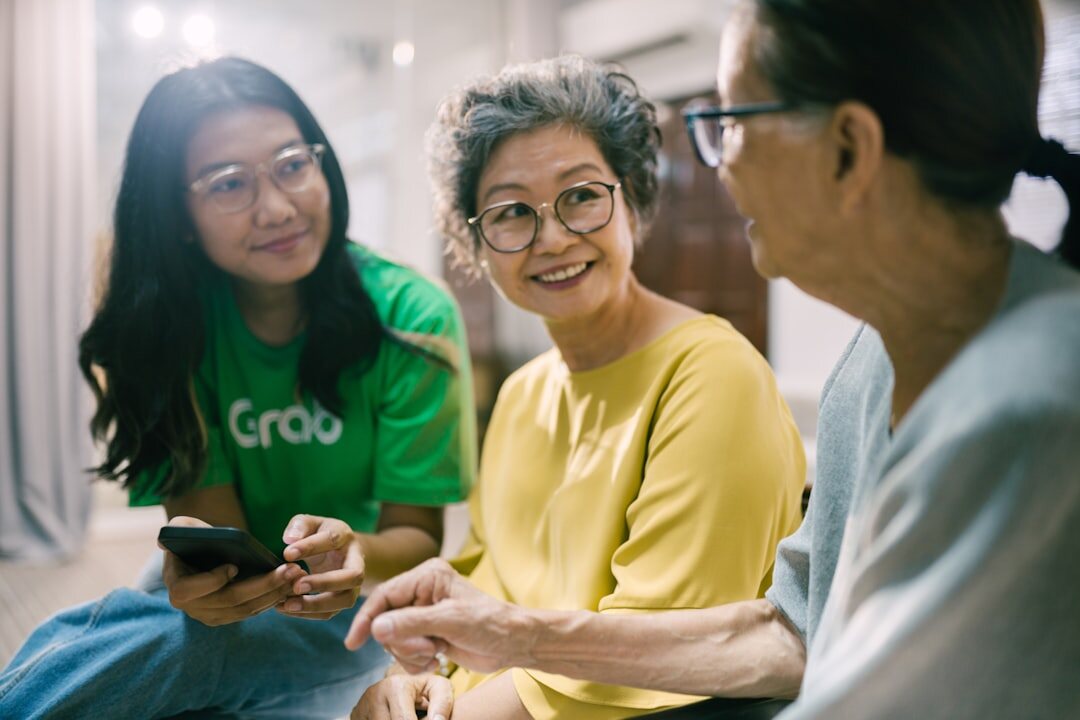 Adult daughter visiting her elderly mother and looking at a tablet together