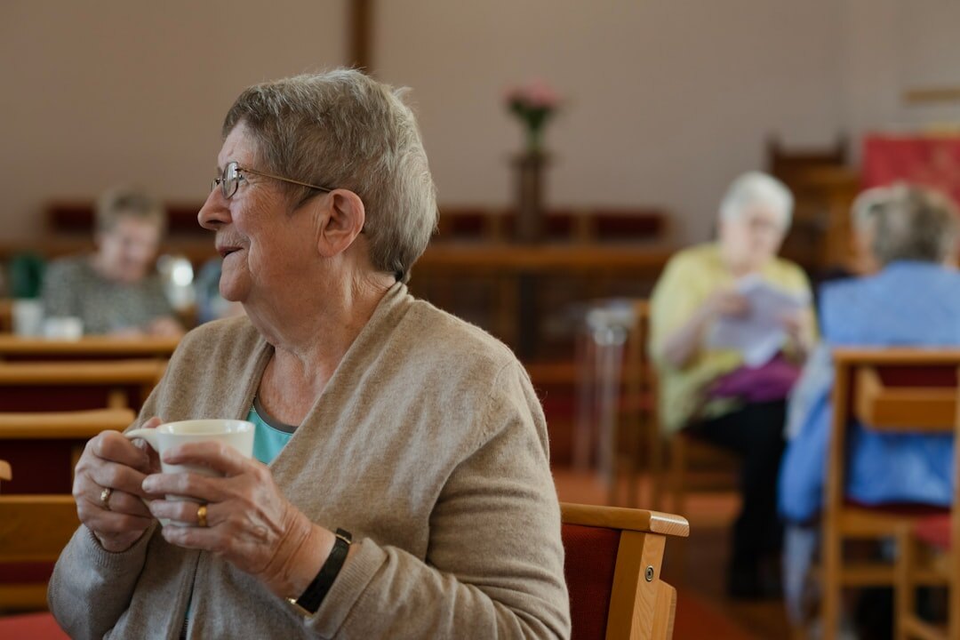 Group of smiling senior friends enjoying coffee together in a bright community room